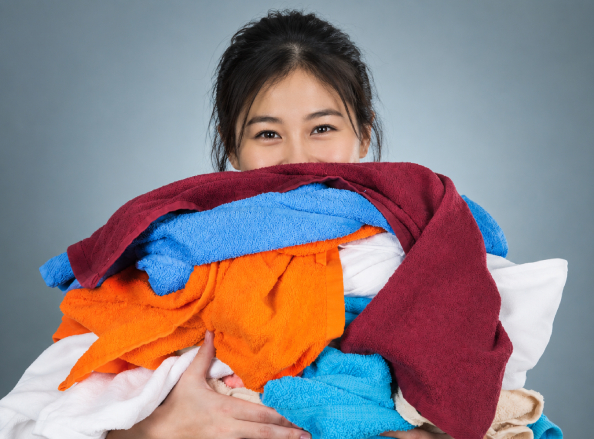 Young Vietnamese laundry staff holding freshly cleaned towels at Hoi An Fly Laundry